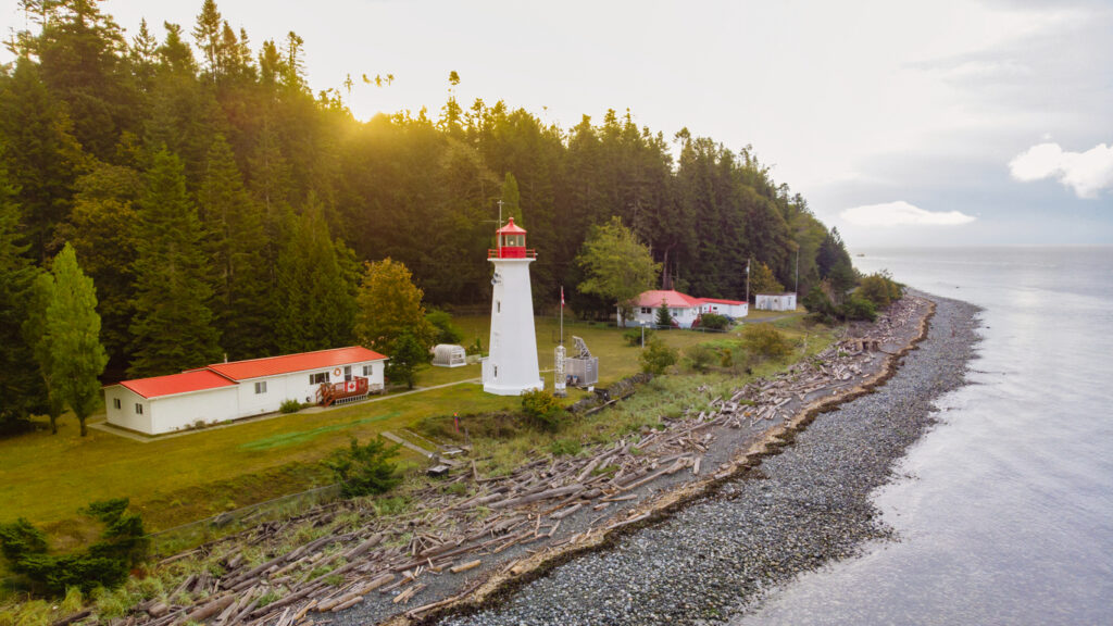 Fishing near Quadra Island old historical lighthouse at Cape Mudge Vancouver Island, Canada, Lighthouse at the beach during cloudy summer weather